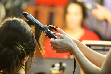 Photo of stylist with curling hair-do brunette opposite