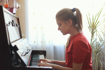 Blonde teenage girl 14-years old playing the piano at home