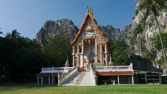 Ancient traditional Buddhist temple Wat Khao Daeng, surrounded by limestone cliffs and a rainforest. Thailand.