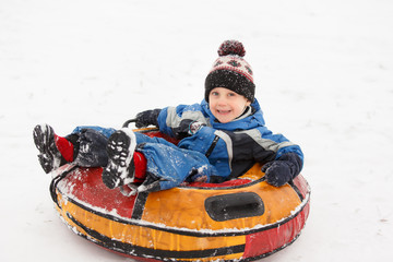 Fototapeta na wymiar Photo of boy on tubing in winter park
