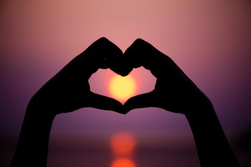 Fototapeta premium Silhouette the woman hands to be heart shape on sunset background. Happy, Love, Valentine's day idea, sign, symbol, concept.
