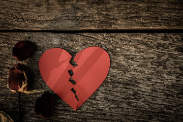 Top view dried red rose, dead red rose with red paper in shape of broken hearted on wooden background with vintage style. Broken hearted, Love, Wedding and Valentines day concept.