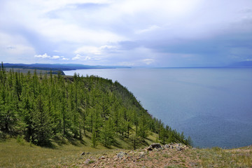 Green wooded promontory with pine trees on the background of water and vistas, Lake Baikal Olkhon Khuzhir town