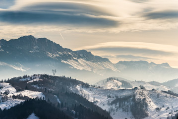 Obraz na płótnie Canvas Beautiful winter landscape in the mountains with lenticular clouds and snow,Pestera, Bucegi, Romania