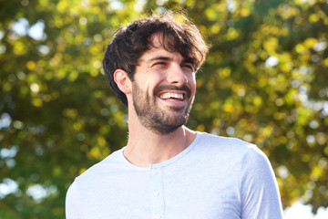 Close up handsome young man with beard smiling outdoors