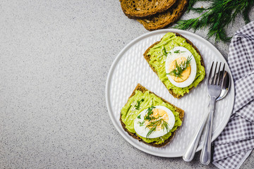 Smashed avocado egg toasts on concrete background. Top view, space for text. 