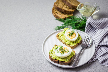 Avocado egg toasts on concrete background.  Selective focus, close up, space for text.