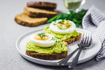 Avocado egg salad on toasts on concrete background. Selective focus, close up, space for text.