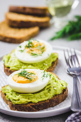 Soft boiled egg and avocado toasts on concrete background. Selective focus, close up, space for text.