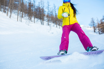 Picture of athlete girl in helmet and mask snowboarding from snowy slope with trees