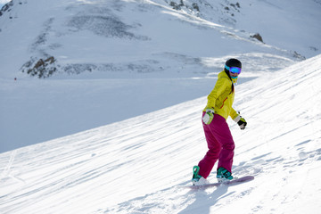 Photo of female athlete wearing helmet and mask, snowboarding from mountain slope