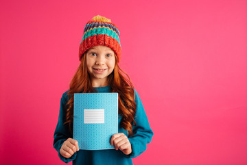 Young beautiful girl showing blue copy book and smiling isolated