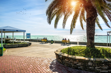 Вид на Черное море в Сочи и отдыхающих на скамейке looking at the emerald Black Sea in the rays of cold sun