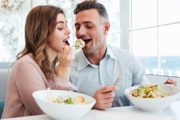 Portrait of happy romantic couple having dinner and eating salat together, while having lunch break...