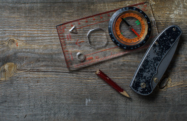 Fototapeta na wymiar Pencil, kompass and pocet knife lies on a wood background