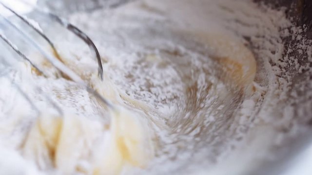 Slow motion close-up as the chef stir with a whisk the ingredients for the dough