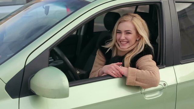 Beautiful business woman giving thumb up inside her new car. Happy smiling girl in the car looking in window and showing thumb up. Cheerful girl sitting inside car with thumb up.