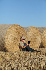 Naklejka na ściany i meble Farmer examining wheat field after harvest using tablet