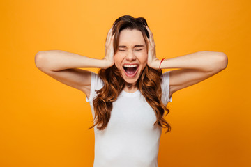 Naklejka premium Screaming brunette woman in t-shirt covering her ears