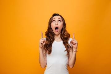 Surprised brunette woman in t-shirt pointing and looking up