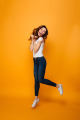 Fototapeta na wymiar Full length image of Playful brunette woman in t-shirt jumping