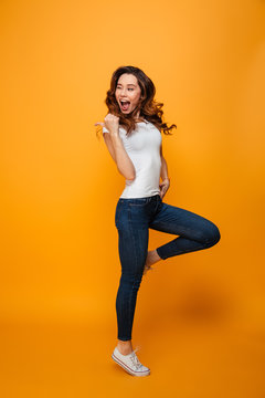 Full length image of Joyful brunette woman in t-shirt jumping