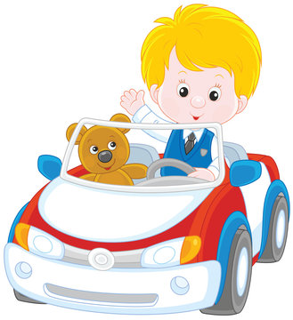 Little boy with his teddy bear in a toy car