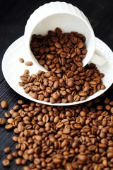 Roasted coffee beans in white mug on table 
