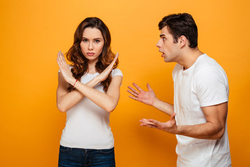 Displeased man screaming on his girlfriend which showing stop gesture