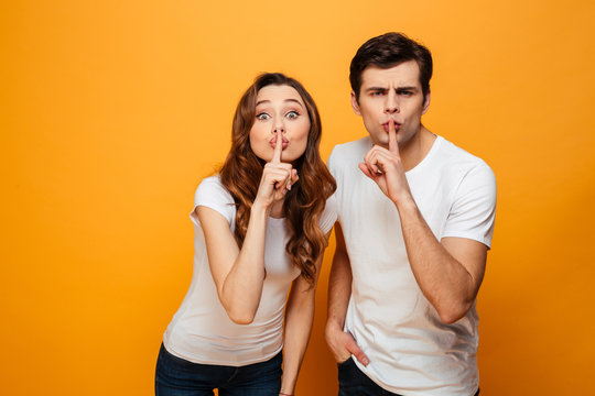 Mystery young couple posing together and showing silence gestures