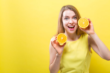 Happy young woman holding oranges on a solid background