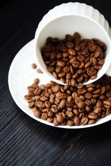 Roasted coffee beans in white mug on table  