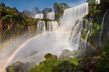 Full rainbow at amazing Iguazu falls, summer landscape with scenic waterfalls