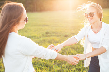 Women in white shirts are spinning on the green field under sunset