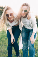 Two young women are having fun on the green field in the evening.