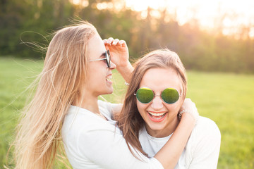 Two women in sunglasses are having fun on the green field