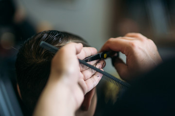 Obraz premium The boy getting haircut by scissor in barbershop. Barber use scissor