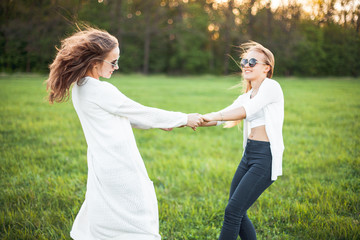 Two pretty females in white shirts are waving on the green field.