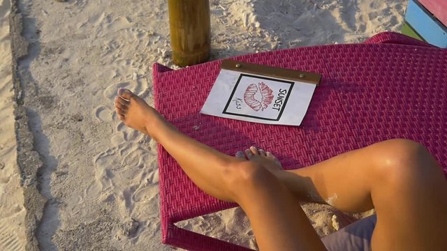 Female legs resting on a lounge chair in the beach