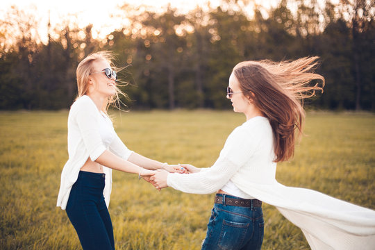 Two nice women are whirling on the green field. Best friends