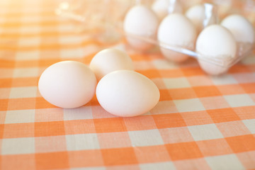 Chicken eggs on a table with a checkered tablecloth.