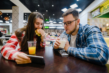 couple make pause for shopping eat burgers in mall cafe