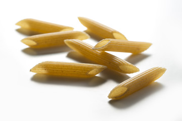 Some pieces of Penne wholemeal pasta isolated on white background