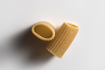Obraz na płótnie Canvas Two pieces of macaroni wholemeal pasta isolated on white background