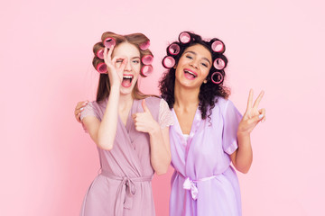 Two girls with hair curlers. They are celebrating women's day March 8.