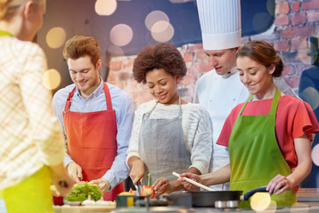 happy friends and chef cook cooking in kitchen