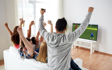 friends watching soccer on tv and celebrating goal