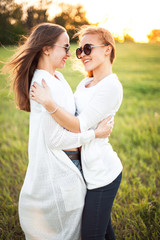 Fototapeta premium Best friends are hugging on a green field under the sunlight.