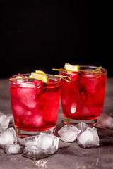 Fototapeta na wymiar Two Glasses of Berries Cold Drink Tasty Cranberry Lemonade with Ice Dark Photo Black Background Vertical