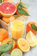 Citrus fruits with green leaves and juice. Lemons, limes, clementines, grapefruit on stone background